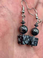 Load image into Gallery viewer, These earrings feature large square shape snowflake obsidian beads complemented with round hematite beads. The neutral cool tones of the stone beads create a unique and versatile style. Measurements: 1 1/4” in length
