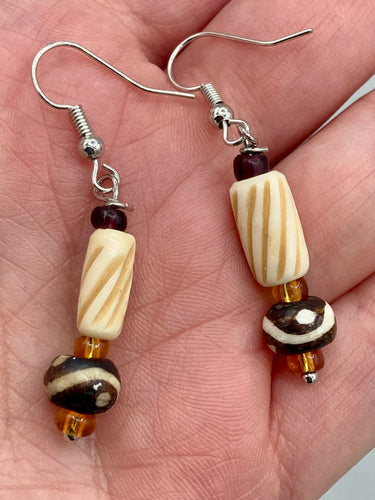 This earring set features cylinder and round bone beads with decorative wavy lines and dot designs, as well as gold-tone glass beads. Neutral colors make these earrings perfect for any occasion - dress them up or down for a look that is sure to be one-of-a-kind.  Measurements: 1 5/8 ” in length  