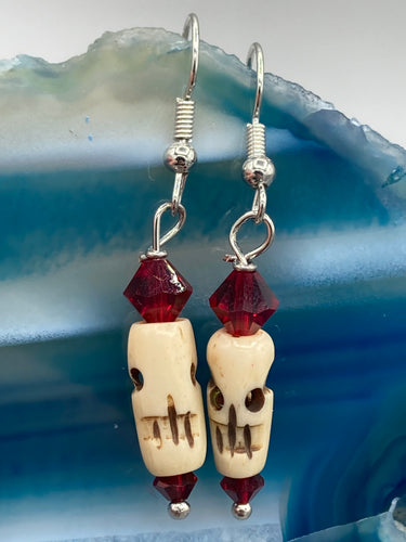 These handcrafted earrings feature a mini-bone carved skull coupled with dark red glass beads. Perfect for Goth, Emo, and Witchy styles, these earrings are sure to provide a unique addition to any Day of the Dead outfit. Our earrings can effortlessly transition between dressy and casual styles.   Measurements: 1 1/4 ” in length  