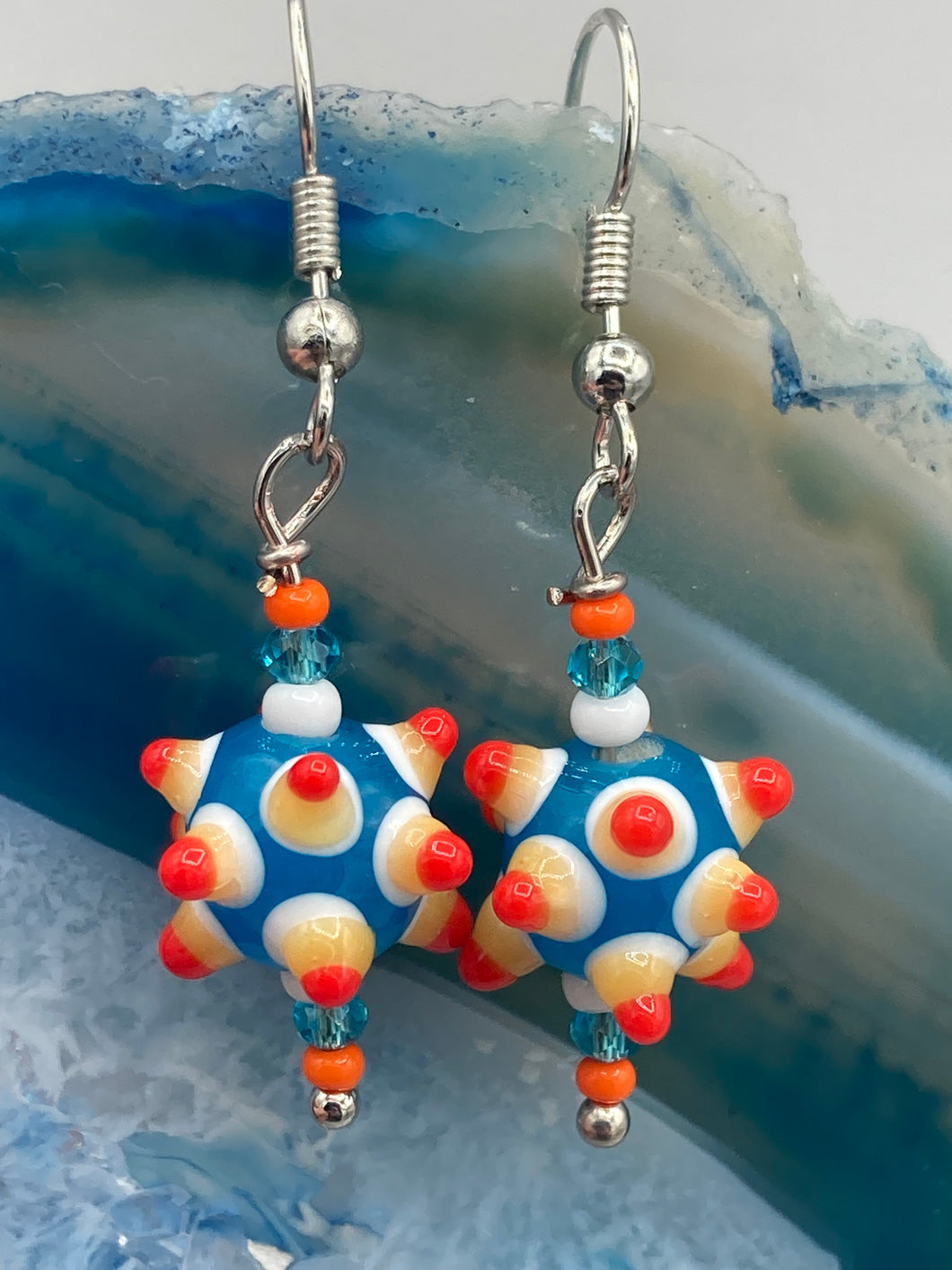 Vibrant color bumpy round lampworked glass bead set of earrings. Colorful teal, white, yellow, and bright orange festive piñata shaped bead.  This also reminds me of the shape of a virus. Either way, this is a super fun, unique, bold piece of jewelry, it's sure to make a statement piece.  Measurements: 1 1/4” in length