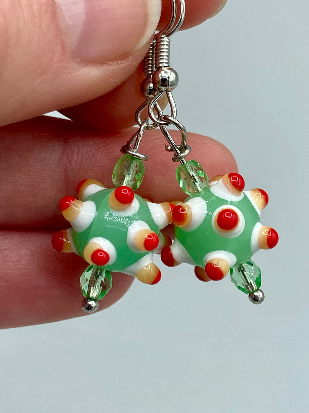 Vibrant color bumpy round lampworked glass bead set of earrings. Colorful light green, white, yellow, and bright red festive piñata shaped bead.  This also reminds me of the shape of a virus. Either way, this is a super fun, unique, bold piece of jewelry, it's sure to make a statement piece.  Measurements: 1 1/4” in length