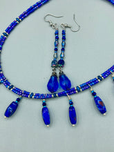 Load image into Gallery viewer, This stunning, one of a kind pair of celestial beaded earrings is a bold addition to any jewelry collection. Crafted with vibrant blue glass beads, the color contains varied shades of blue, purple, and hints of gold to create unique texture. The design is inspired by the awe-inspiring beauty of the majestic galaxy.    Measurements: 2 3/4” in length
