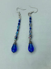 Load image into Gallery viewer, This stunning, one of a kind pair of celestial beaded earrings is a bold addition to any jewelry collection. Crafted with vibrant blue glass beads, the color contains varied shades of blue, purple, and hints of gold to create unique texture. The design is inspired by the awe-inspiring beauty of the majestic galaxy.    Measurements: 2 3/4” in length
