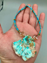 Load image into Gallery viewer, This vibrant and striking double strand necklace features a combination of glass beads in blue and green shades of turquoise, gold and champagne. The two delicate strands are accented with a gold-tone flower-shaped bead, a howlite stone chip dyed in turquoise, and shimmery, cross-faceted champagne-colored glass beads to complete the dramatic look.  Measurements:   Necklace is 17” and can be adjusted up to 19"
