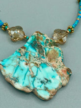 Load image into Gallery viewer, This vibrant and striking double strand necklace features a combination of glass beads in blue and green shades of turquoise, gold and champagne. The two delicate strands are accented with a gold-tone flower-shaped bead, a howlite stone chip dyed in turquoise, and shimmery, cross-faceted champagne-colored glass beads to complete the dramatic look.  Measurements:   Necklace is 17” and can be adjusted up to 19"

