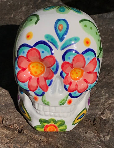 This hand-painted, mini ceramic sugar skull art piece is inspired by peacock feathers, perfect colorful artwork for Dia de Los Muertos. The intricate design captures the beauty of peacock feathers bring a unique and beautiful piece to your ofrenda and celebrate your loved ones in style. Measurements: H 2 3/4” x W 2” x D 2”