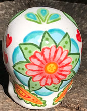 Load image into Gallery viewer, Inspired by nature, this ceramic skull statuette is full of vibrant color and intricate details. The primary color is white with multi-color floral motifs that are painted across the 

