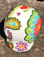 Load image into Gallery viewer, Inspired by nature, this ceramic skull statuette is full of vibrant color and intricate details that I hand painted. The primary color is white with multi-color floral motifs that are painted across the skull, along with hearts and leaves and lively colorful accents around the entire skull. 
