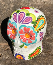 Load image into Gallery viewer, Inspired by nature, this ceramic skull statuette is full of vibrant color and intricate details that I hand painted. The primary color is white with multi-color floral motifs that are painted across the skull, along with hearts and leaves and lively colorful accents around the entire skull. 
