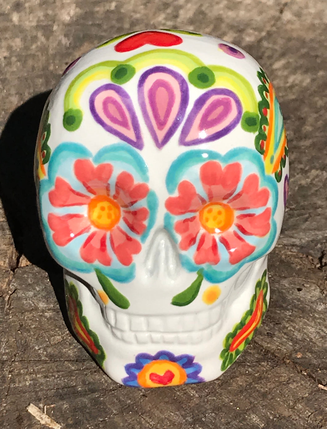Inspired by nature, this ceramic skull statuette is full of vibrant color and intricate details that I hand painted. The primary color is white with multi-color floral motifs that are painted across the skull, along with hearts and leaves and lively colorful accents around the entire skull. 
