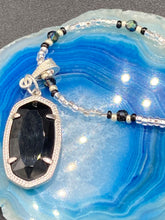Load image into Gallery viewer, This dainty necklace is full of black and silver shimmery glass beads. A length black oval shaped glass bead hangs low to add length to this necklace.  It&#39;s the perfect necklace to add a little elegance to any outfit. Will go with any outfit, dress it up or down, this necklace will complete any look. This beauty is a must-have, add it to your jewelry collection.  Measurements: Necklace is 15 1/2” adjustable up to 18&quot;- pendant is 1 1/2” Height
