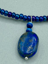 Load image into Gallery viewer, This Lapis pendant necklace features dark blue cats eye beads and two strands of gold glass beads with dark blue double hole beads. The large multi-colored glass beads provide remarkable shimmer and a full range of colors, such as purples, blues, greens, and golds, that enhances the lapis stone pendant.   Measurements:   Necklace is 19” in length 
