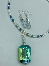 Load image into Gallery viewer, These earrings feature two shimmery iridescent glass beads with a single silver glass bead.  Measurements: 1 1/2” in length

