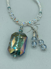 Load image into Gallery viewer, These earrings feature two shimmery iridescent glass beads with a single silver glass bead.  Measurements: 1 1/2” in length 
