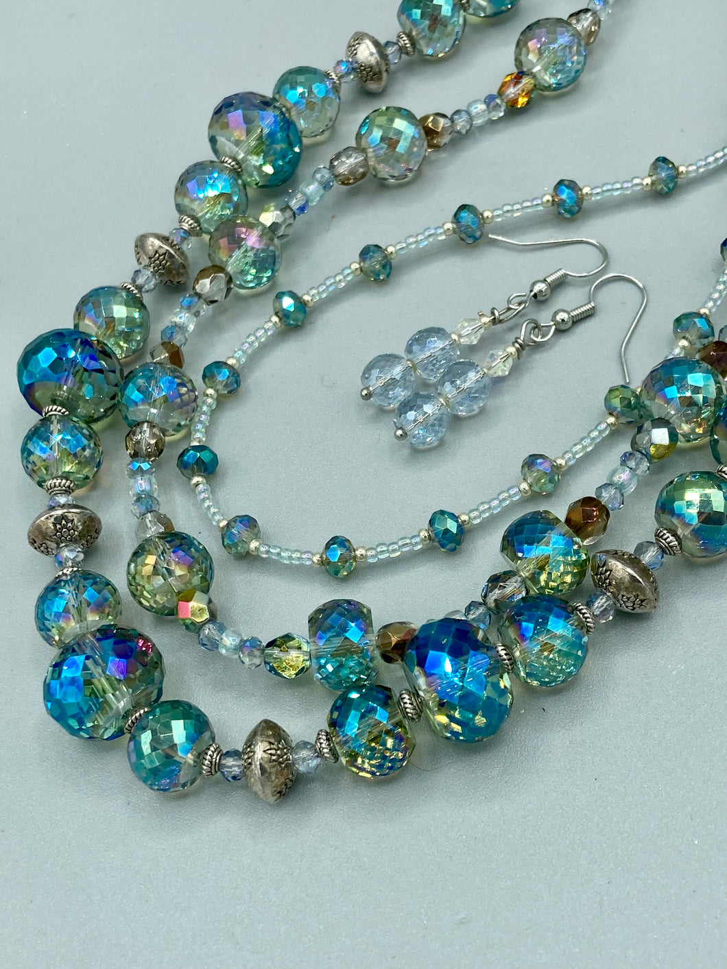 These earrings feature two shimmery iridescent glass beads with a single silver glass bead.  Measurements: 1 1/2” in length