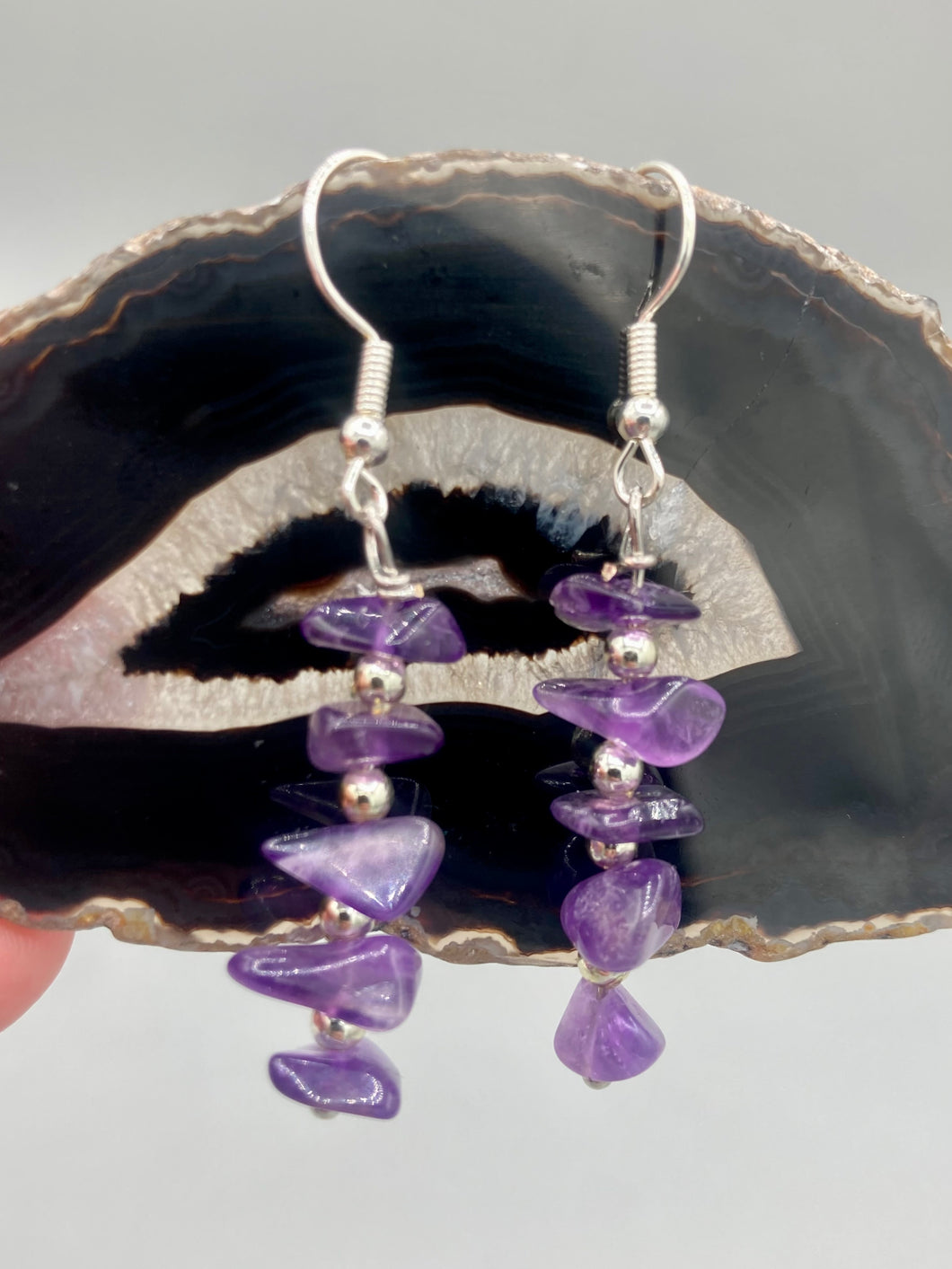 This single strand of beads is composed of natural amethyst stone chips and silver glass beads for a unique, bohemian look. Measurements: 1 1/2 ” in length 