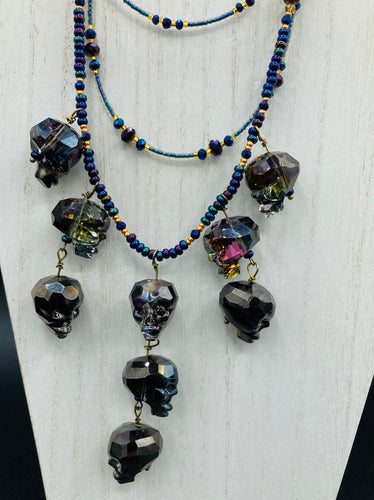 Massively beautiful and bold skull necklace is the ultimate statement piece to add to your jewelry collection! Three strands necklace, contains 5 strands of large skull beads that give a cascade look to this beautiful necklace. Edgy gun metal faceted shimmery multi-color glass hues of silver, purple, pink, blue, and gold. This bold and beautiful necklace drapes across your neck, comes with dainty matching earrings to complete the look. Necklace is 15 1/2” adjustable up to 18