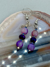 Load image into Gallery viewer, These elegant, glass beaded earrings feature dainty light and dark purple hues, making them a great addition to any summer wardrobe. Perfect for hippie and nature-inspired looks, they are sure to accentuate any style.  Measurements: 1 ” in length
