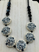 Load image into Gallery viewer, This eye-catching, sizable and conspicuous black stone beads create a powerful accent piece. Crafted of reconstituted quartzite lentil beads in a tree pattern, these beads measure approximately 24mm. To enhance their effect, a round necklace of black glass beads is included. Perfect for casual or formal wear, this necklace adds an elegant finish to any ensemble. Matching earrings feature white rose reconstituted quartzite beads, completing the set.  Measurements: Necklace is 18 &quot; in length 
