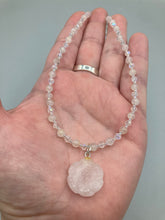 Load image into Gallery viewer, This elegant necklace is adorned with a beautiful rose quartz pendant featuring an intricate floral cutout, complemented by small round rose quartz beads with an iridescent glass finish.  Measurements:  Necklace is 18 1/2”
