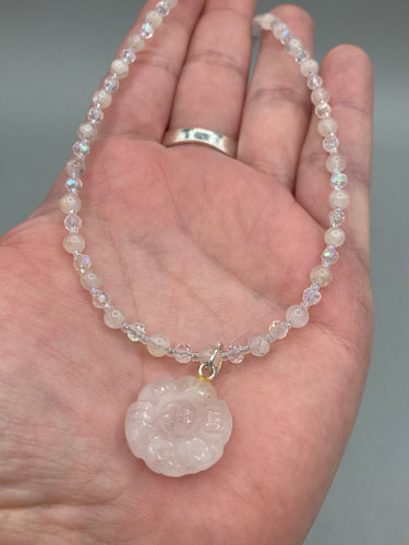 This elegant necklace is adorned with a beautiful rose quartz pendant featuring an intricate floral cutout, complemented by small round rose quartz beads with an iridescent glass finish.  Measurements:  Necklace is 18 1/2”