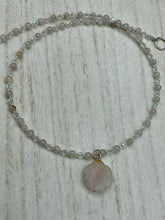 Load image into Gallery viewer, This elegant necklace is adorned with a beautiful rose quartz pendant featuring an intricate floral cutout, complemented by small round rose quartz beads with an iridescent glass finish.  Measurements:  Necklace is 18 1/2”
