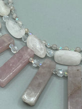 Load image into Gallery viewer, This impressive three-strand necklace is crafted from natural rose quartz stones and iridescent glass beads. The shortest strand is composed of petite round rose quartz beads, while the second strand contains an array of rectangular-shaped rose quartz and iridescent glass beads. The longest strand has long, vertical rectangular-shaped rose quartz beads, creating an elegant display across the chest.  This necklace is an impressive, dynamic accessory.  Necklace is 17: in length, can be adjusted to 19&quot;
