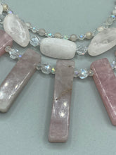 Load image into Gallery viewer, This impressive three-strand necklace is crafted from natural rose quartz stones and iridescent glass beads. The shortest strand is composed of petite round rose quartz beads, while the second strand contains an array of rectangular-shaped rose quartz and iridescent glass beads. The longest strand has long, vertical rectangular-shaped rose quartz beads, creating an elegant display across the chest.  This necklace is an impressive, dynamic accessory.  Necklace is 17: in length, can be adjusted to 19&quot;

