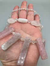 Load image into Gallery viewer, This impressive three-strand necklace is crafted from natural rose quartz stones and iridescent glass beads. The shortest strand is composed of petite round rose quartz beads, while the second strand contains an array of rectangular-shaped rose quartz and iridescent glass beads. The longest strand has long, vertical rectangular-shaped rose quartz beads, creating an elegant display across the chest.  This necklace is an impressive, dynamic accessory.  Necklace is 17: in length, can be adjusted to 19&quot;
