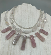 Load image into Gallery viewer, This impressive three-strand necklace is crafted from natural rose quartz stones and iridescent glass beads. The shortest strand is composed of petite round rose quartz beads, while the second strand contains an array of rectangular-shaped rose quartz and iridescent glass beads. The longest strand has long, vertical rectangular-shaped rose quartz beads, creating an elegant display across the chest.  This necklace is an impressive, dynamic accessory.  Necklace is 17: in length, can be adjusted to 19&quot;
