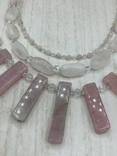 Load image into Gallery viewer, This impressive three-strand necklace is crafted from natural rose quartz stones and iridescent glass beads. The shortest strand is composed of petite round rose quartz beads, while the second strand contains an array of rectangular-shaped rose quartz and iridescent glass beads. The longest strand has long, vertical rectangular-shaped rose quartz beads, creating an elegant display across the chest.  This necklace is an impressive, dynamic accessory.  Necklace is 17: in length, can be adjusted to 19&quot;
