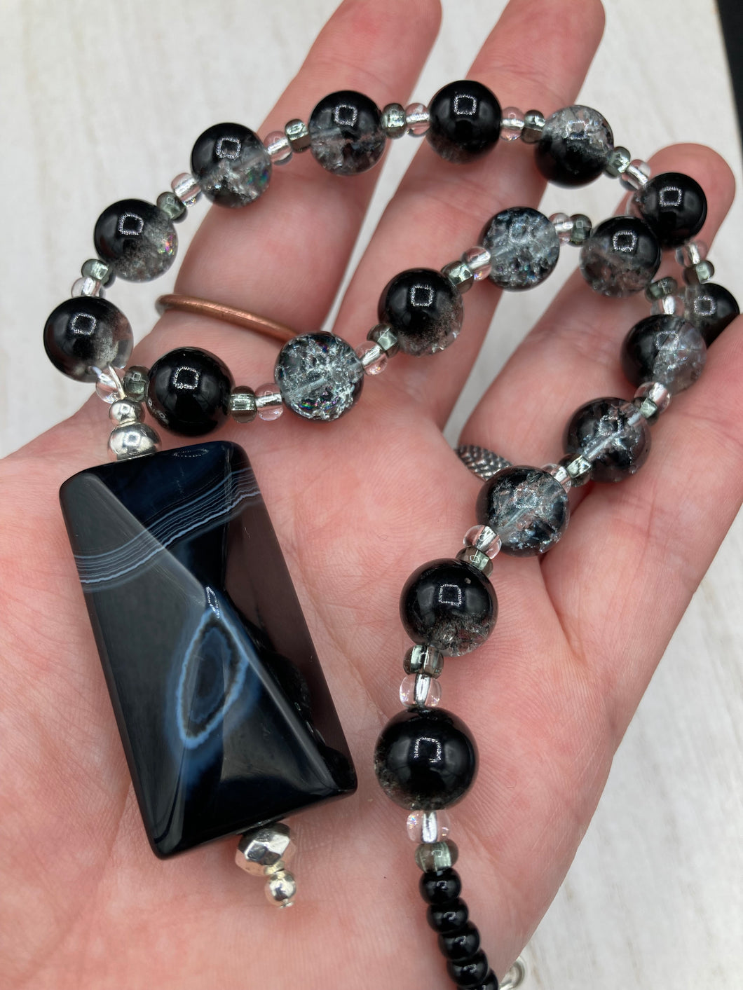 This black agate natural stone necklace features a unique rectangular pyramid shape and multi-colored glass beads. Perfect for all kinds of looks, from cocktail attire to shabby chic to elegant goth styles, this necklace is as versatile as it is stylish and will complete any outfit. The set includes matching earrings, making it a must-have addition to any jewelry collection.  Measurements:  Necklace is 18 1/2” 