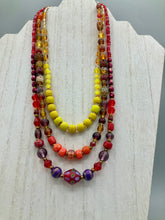 Load image into Gallery viewer, This necklace consists of three strands with a multitude of shades ranging from red to orange, gold, and amber, providing a captivating visual combination. Crafted with a combination of glass, ceramic and metal beads, this eye-catching piece of jewelry radiates power and strength.  Measurements:  Necklace is 16” in length, can be adjusted up to 17 1/2&quot;
