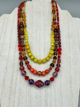 Load image into Gallery viewer, This necklace consists of three strands with a multitude of shades ranging from red to orange, gold, and amber, providing a captivating visual combination. Crafted with a combination of glass, ceramic and metal beads, this eye-catching piece of jewelry radiates power and strength.  Measurements:  Necklace is 16” in length, can be adjusted up to 17 1/2&quot;
