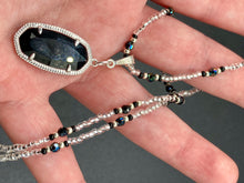 Load image into Gallery viewer, This dainty necklace is full of black and silver shimmery glass beads. A length black oval shaped glass bead hangs low to add length to this necklace.  It&#39;s the perfect necklace to add a little elegance to any outfit. Will go with any outfit, dress it up or down, this necklace will complete any look. This beauty is a must-have, add it to your jewelry collection.  Measurements: Necklace is 15 1/2” adjustable up to 18&quot;- pendant is 1 1/2” Height
