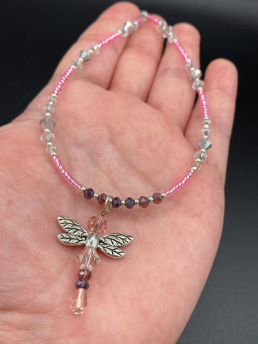 This softy pink and purple choker style necklace with a silver dragonfly pendant is perfect for nature lovers. Glass beads make the necklace adjustable, and it comes with matching dragonfly earrings for a truly magical, fairy princess look. An ideal accessory for summer.  Measurements: Necklace is 15 1/2” adjustable up to 18