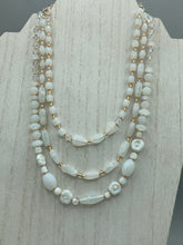 Load image into Gallery viewer, This necklace is the perfect finishing touch to any outfit. Featuring three strands of white and gold glass beads for a classic and elegant look. The small clear and gold glass beads add a touch of sophistication. Adjustable for a comfortable fit.  Measurements:   Necklace is 17” in length, can be adjusted up to 19 1/2" 
