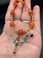 Load image into Gallery viewer, This bright orange, adjustable, choker-style necklace is adorned with beaded glass and a striking crescent moon charm and dragonfly pendant. Accessorize with matching dragonfly earrings for an eye-catching, complementary look that captures the warmth of summer. Perfect for any outfit, its vibrant colors will make a statement and complete any look.  Measurements: Necklace is 16 1/2”adjustable up to 19&quot; 

