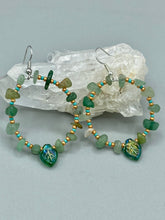 Load image into Gallery viewer, Natural aventurine stone chips, turquoise, and gold glass beads are strung together to form these stylish hoop earrings. The dark green pressed glass leaf charm complements the design, creating an iridescent, shimmery finish with subtle hues of gold, purple, blue, and pink. Measurements: 2&quot; length
