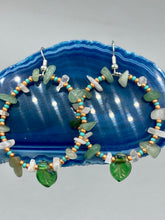 Load image into Gallery viewer, These handmade hoop earrings feature natural Aventurine and White Moon Stone chips along with turquoise and gold glass beads. The light green-toned pressed glass leaf charm beautifully shimmers with iridescent hues of gold, purple, blue, and pink. Measurements: 2&quot; length
