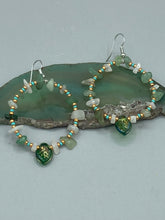 Load image into Gallery viewer, These handmade hoop earrings feature natural Aventurine and White Moon Stone chips along with turquoise and gold glass beads. The light green-toned pressed glass leaf charm beautifully shimmers with iridescent hues of gold, purple, blue, and pink. Measurements: 2&quot; length
