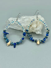Load image into Gallery viewer, These earrings boast a beautiful combination of natural lapis and white moon stone chip stones, artfully inlaid with gold glass beads in a hoop formation. Dainty conch shells add a subtle touch of nature for a look that perfectly captures the beach vibes of summer. An ideal choice to complement any style.  Measurements: 2 1/4&quot; length
