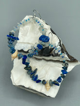 Load image into Gallery viewer, These earrings boast a beautiful combination of natural lapis and white moon stone chip stones, artfully inlaid with gold glass beads in a hoop formation. Dainty conch shells add a subtle touch of nature for a look that perfectly captures the beach vibes of summer. An ideal choice to complement any style.  Measurements: 2 1/4&quot; length
