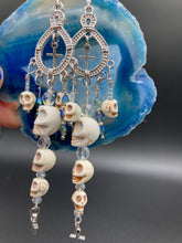 Load image into Gallery viewer, Large Chandelier Style Earrings Howlite Skull Beads Silver Plated Crosses. Ultimate Chingona, Cabrona, Latina Chicana, Goth, Vampire Goth, Dark Witchy Style. You can dress these up or down, it will definitely give your outfit a unique look. Cascade of dangling skulls and crosses have plenty of fun movement.  Measurements: 4” in length
