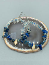 Load image into Gallery viewer, These earrings boast a beautiful combination of natural lapis and white moon stone chip stones, artfully inlaid with gold glass beads in a hoop formation. Dainty conch shells add a subtle touch of nature for a look that perfectly captures the beach vibes of summer. An ideal choice to complement any style.  Measurements: 2 1/4&quot; length

