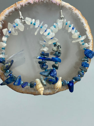 These earrings boast a beautiful combination of natural lapis and white moon stone chip stones, artfully inlaid with gold glass beads in a hoop formation. Dainty conch shells add a subtle touch of nature for a look that perfectly captures the beach vibes of summer. An ideal choice to complement any style.  Measurements: 2 1/4