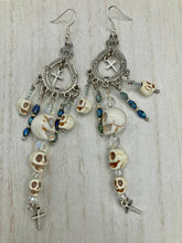 Load image into Gallery viewer, Large Chandelier Style Earrings Howlite Skull Beads Silver Plated Crosses. Ultimate Chingona, Cabrona, Latina Chicana, Goth, Vampire Goth, Dark Witchy Style. You can dress these up or down, it will definitely give your outfit a unique look. Cascade of dangling skulls and crosses have plenty of fun movement.  Measurements: 4” in length

