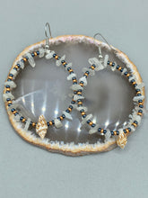 Load image into Gallery viewer, Dainty conch shells and natural white moon stone chips, these dark silver and gold glass beaded hoop earrings are the perfect accessory for any nature-loving, beach-themed outfit. Their versatility allows them to easily complement any outfit.  Measurements: 2 1/4&quot; length

