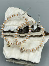 Load image into Gallery viewer, Delicate white moon stone chip and glass beaded hoop earrings featuring chic gold accents and tiny conch shells. Perfect for nature lovers, these boho-inspired summer earrings will add a subtle sophistication to any outfit. Measurements: 2" length
