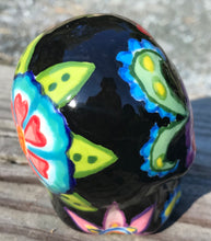 Load image into Gallery viewer, This hand-painted ceramic skull art is an homage to the traditional Mexican Day of the Dead. The inspiration for the skull&#39;s exquisite detail was taken from a beautiful flower photographed at the United States Botanic Garden - a whimsical surprise of small flowers floating in water. Bring La Muerte Calavera de Ofrenda, or &#39;skull of offering&#39;, into your home for a captivating reminder of Mexican tradition. H 2 3/4” x W 2” x D 2”

